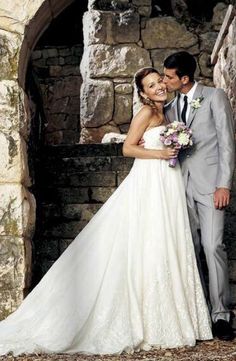 a bride and groom posing for a photo in front of an old stone wall with archways