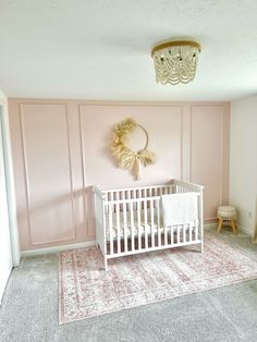 a baby's room with pink walls and white crib in the corner, rug on the floor