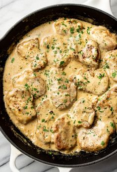 a skillet filled with meat and gravy on top of a marble counter