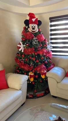 a decorated christmas tree in the corner of a living room with mickey mouse decorations on it