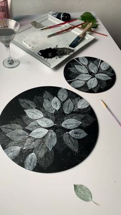 two black and white plates sitting on top of a table next to paintbrushes