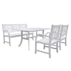 a white table and six chairs with one chair missing the armrests is shown