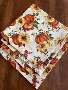 four pumpkins and sunflowers printed napkins on a wooden table top with wood flooring