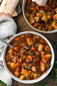 two bowls filled with stew on top of a wooden table