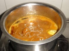 a metal bowl filled with soup on top of a stove