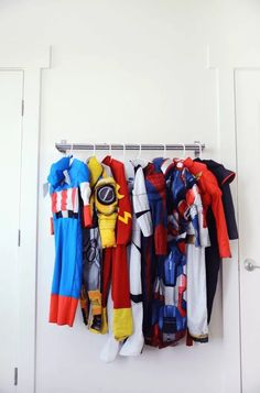 a bunch of clothes that are hanging up on a rack in a room with white walls