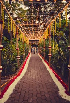 a walkway decorated with flowers and lights for an outdoor wedding ceremony in the jungles