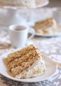 a piece of cake sitting on top of a white plate next to a cup of coffee