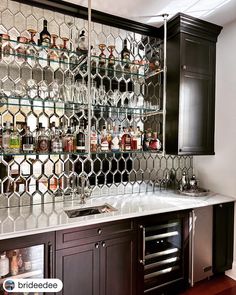 a kitchen with black cabinets and shelves filled with liquor bottles on top of glass shelves