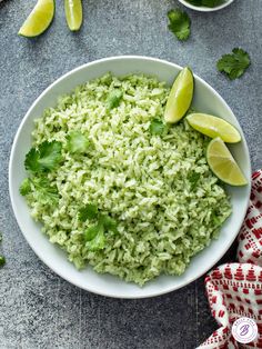 a white bowl filled with rice and cilantro garnished with lime wedges