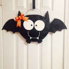 a bat shaped door hanger with a bow on it's head and eyes