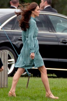 a woman in a green dress is walking her dog