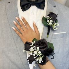 a man in a gray suit and black bow tie with flowers on his lapel