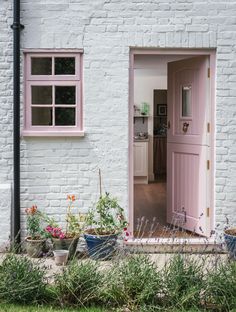 an open pink door to a white brick house