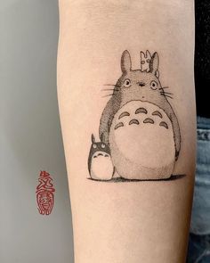 a tattoo with an image of a totoro and a cat