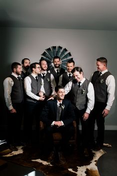 a group of men standing next to each other in front of a wall mounted fan