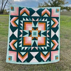 a quilt on the grass with trees in the background