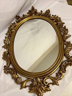 an ornate gold mirror sitting on top of a white sheet