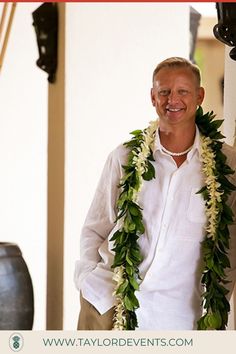 a man wearing a lei standing next to a large vase with flowers on it's neck