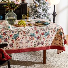 a dining room table with a christmas tree in the background and holiday decorations on it