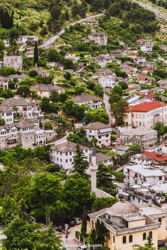 an aerial view of a city with lots of buildings and trees in the foreground