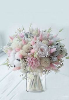 a vase filled with lots of flowers on top of a white table next to a window