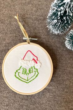 a christmas ornament with a grin face on it and a pine tree in the background