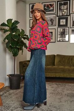 a woman standing in a living room next to a green couch and potted plant