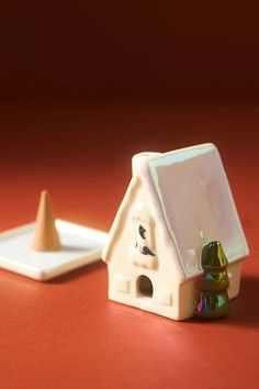 a small toy house next to a white plate