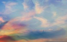 an airplane is flying in the sky with colorful clouds above it and another plane on the ground