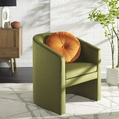 a green chair sitting on top of a white rug next to a potted plant