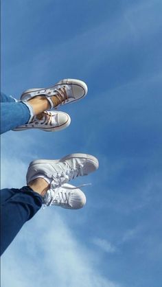 two people standing in the air with their feet up and one person wearing white sneakers