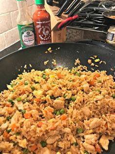 chicken and rice is cooking in a skillet on the stove top next to condiments