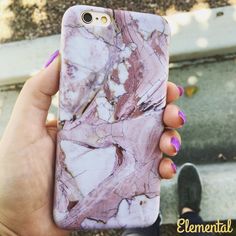 a woman holding up her phone case with pink marble