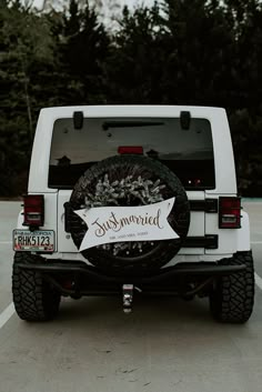 a white jeep parked in a parking lot with a welcome sign on it's back