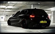 a black car parked in a parking garage with red rims and yellow license plate