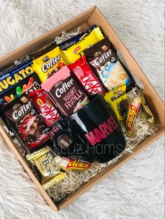 a box filled with assorted chocolates and candy bars on top of a white blanket