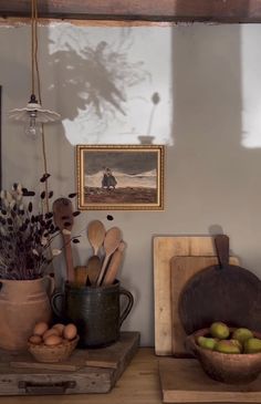 an assortment of kitchen utensils and other items on a shelf in front of a painting