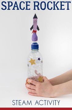 a hand holding a bottle with a rocket on top and stars in the bottom that says space rocket steam activity