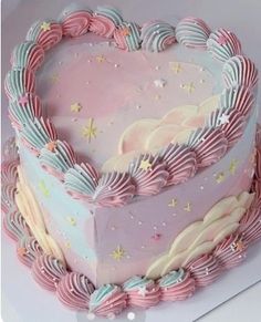 a heart shaped cake with pink frosting and stars on it's sides, sitting on a table