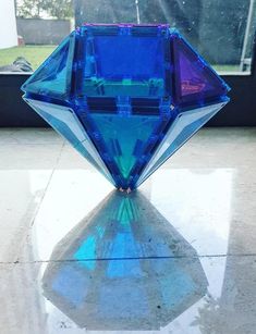 a blue diamond shaped object sitting on top of a tiled floor next to a window