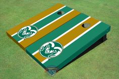 two green and gold striped cornhole game boards on the grass with an image of a dog's head