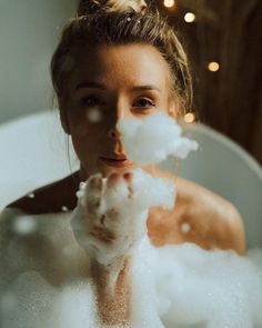 a woman in a bathtub with soap on her hands and bubbles coming out of her mouth