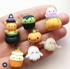 a hand holding a small assortment of halloween charms in it's palm, with pumpkins and ghostes on them