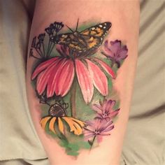 a butterfly and flowers tattoo on the leg