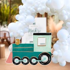 a green train with white balloons hanging from it's side