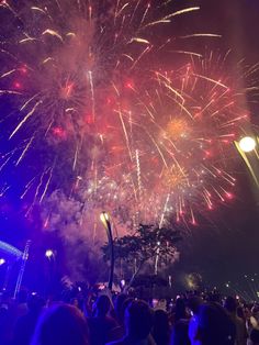 fireworks are lit up in the night sky with people standing around and watching from their seats