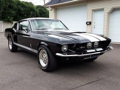 a black mustang parked in front of a garage