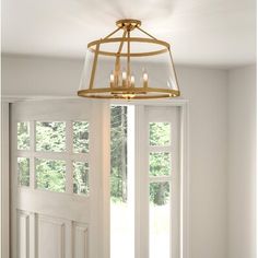 a chandelier hanging from the ceiling in front of a window with white curtains