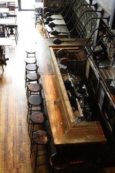 an empty restaurant with lots of chairs and counter tops in front of the bar area